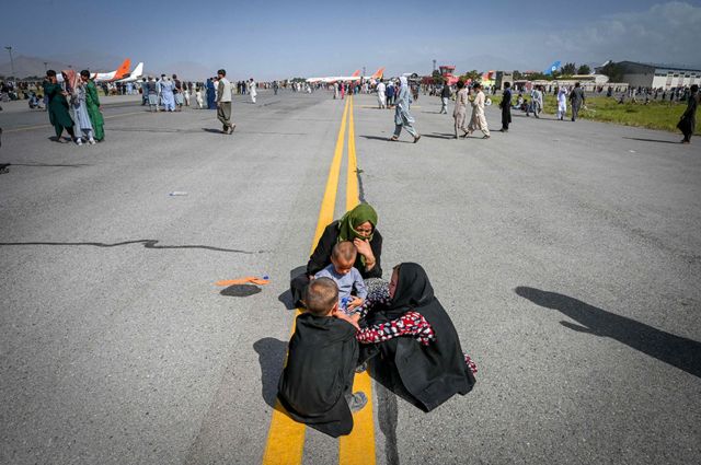 Afghans on the tarmac as they wait in Kabul on August 16, 2021