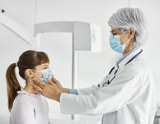 A mature pediatrician is examining a patient.  A health care worker touches a girl's throat in an examination room.  They are in the hospital during the COVID-19 outbreak.  (Photo: Getty Images)