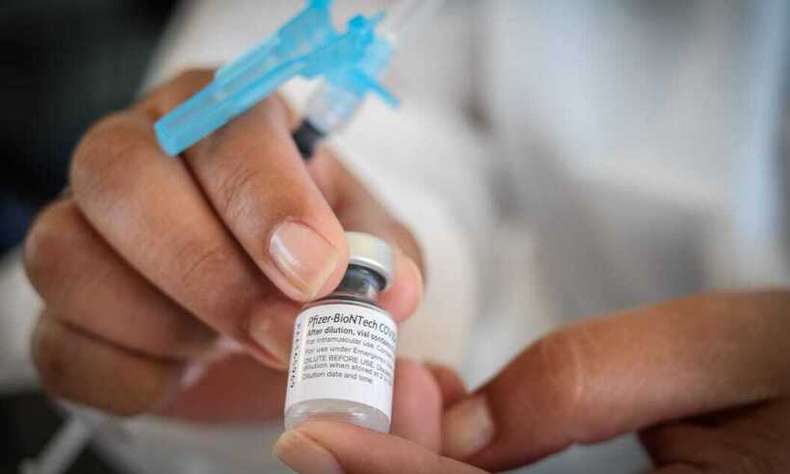 A nurse shows a bottle of Pfizer vaccine