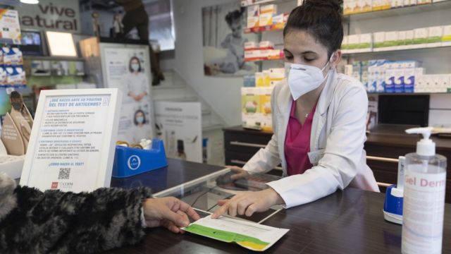 A pharmacist displays an antigen test for a person at the pharmacy 'Las Gemelas' on January 10, 2022 in Madrid, Spain