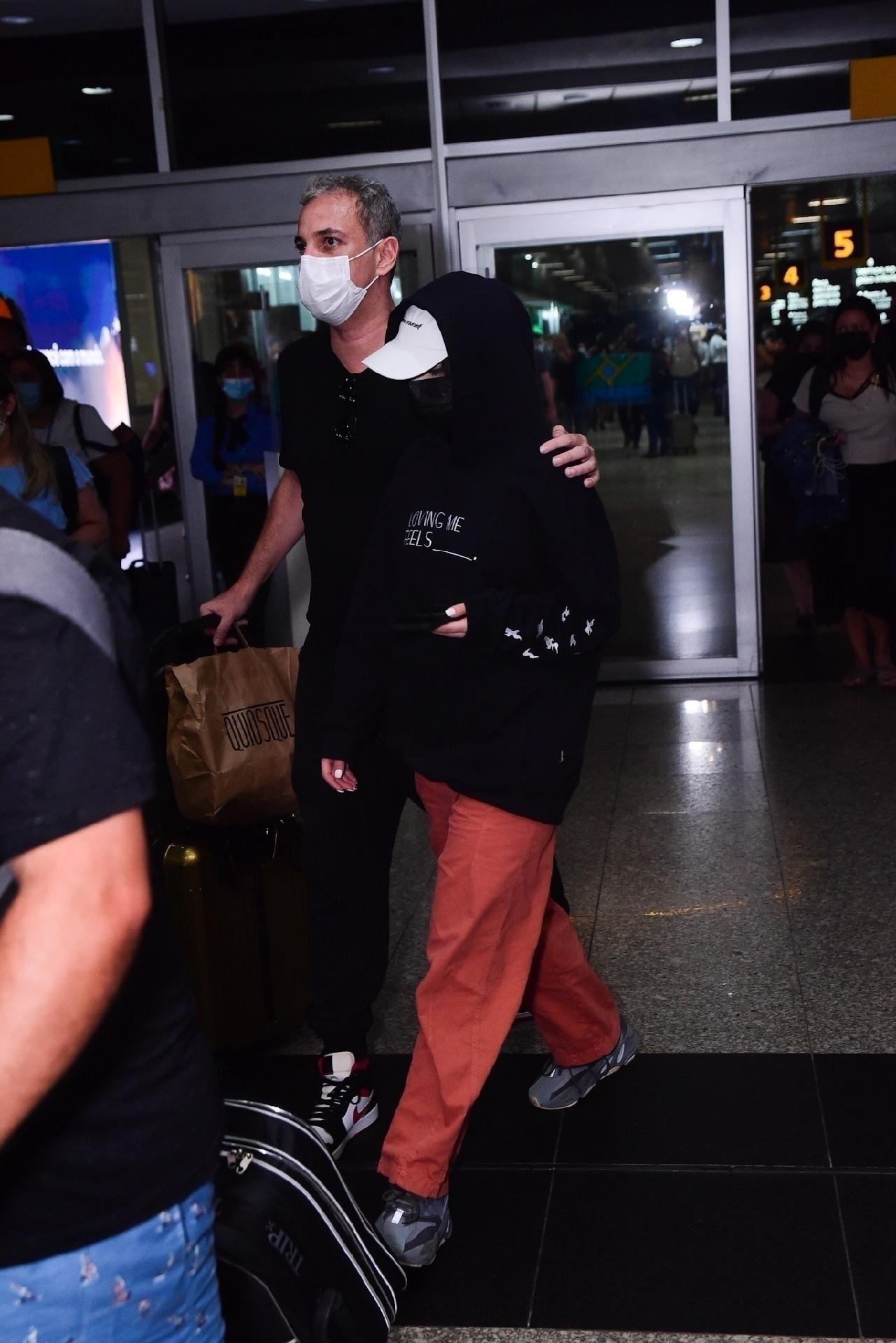 Covered to avoid attracting attention, Jade Picon descends with a security guard at Congonhas Airport in São Paulo - Leo Franco / AgNews